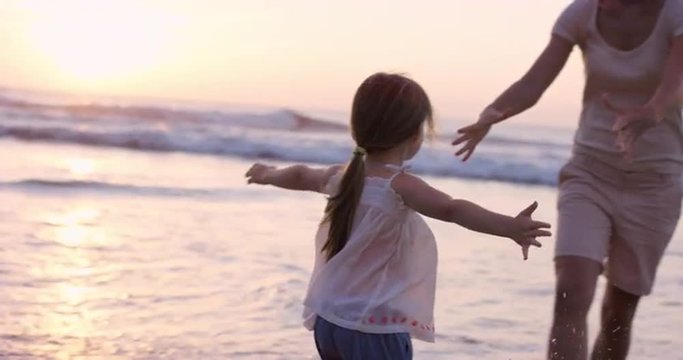 Mother swinging little girl around Happy family on the beach holding hands  at sunset on vacation