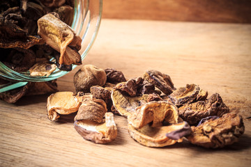 Dry mushrooms in jar on wooden table.