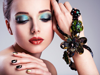 Beautiful woman face with fashion green make-up and jewelry on h