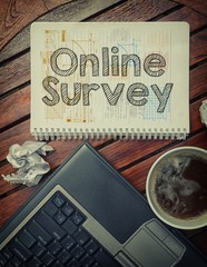 Notebook with text inside Online Survey on table with coffee, la