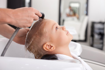 Obraz na płótnie Canvas Pretty healthy boy is getting hairwash in beauty shop