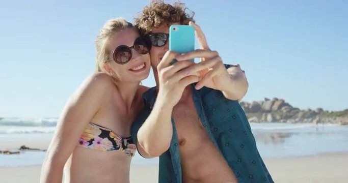 beautiful Caucasian couple taking selfies on the beach