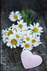 Obraz premium Beautiful fresh daisies decorated with hearts on wooden texture