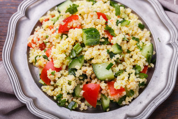 Tabbouleh, an Arabian vegetarian salad made of couscous, tomato, cucumber, onion, garlic, parsley and lemon juice. selective focus