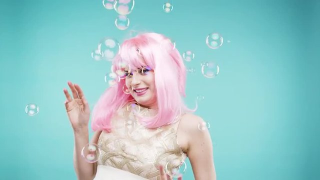 Crazy face pink hair woman dancing in bubble showerslow motion photo booth blue background