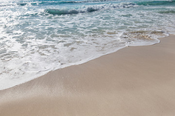 Fototapeta na wymiar Sea waves with foam on white sandy beach