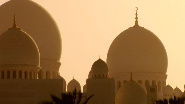 The domes of the beautiful Sheikh Zayed Mosque in Abu Dhabi, United Arab Emirates at sunset.