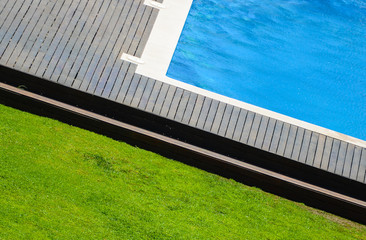 Abstract angle of swimming pool with wooden floor and grass arou
