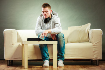 Obraz premium man with headphones sitting on couch with tablet