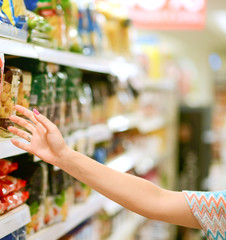 Closeup of female shopper picking products from shelves