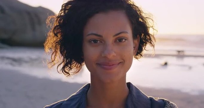 Portrait of beautiful girl smiling on beach at sunset in slow motion