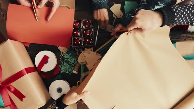 Hands wrapping Christmas presents arial view