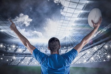 Composite image of rear view of rugby player holding ball