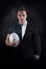 Composite image of tough rugby player holding ball