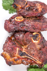 Roasted pieces of lamb on white plate over white background