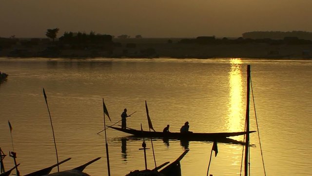 Boats are rowed on the Niger River in beautiful golden light in Mali, Africa.