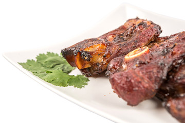 Roasted pieces of lamb on white plate over white background