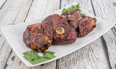 Malaysian dish of roasted lamb in a white plate over wooden background