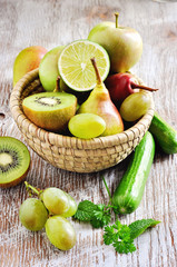 Fresh green fruits and vegetables in a basket: cucumbers, apples, pears, grapes. Toned image