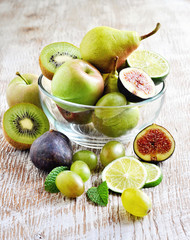 Fresh fruits in glass bowl: apples, pears, grapes, figs, lime. Toned image