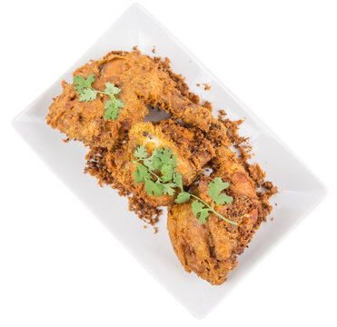 Popular Javanese dish Ayam Penyet or crispy fried chicken in a white plate over wooden background
