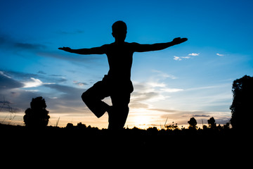 Silhouette of man practicing yoga with beautiful sunset