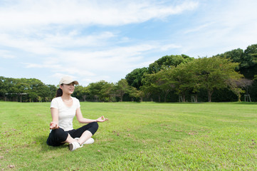 Fototapeta premium 芝生の上に座って瞑想している女性