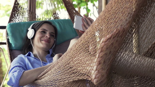 Happy woman watching movie one smartphone lying on hammock, slow motion 240fps
