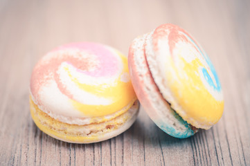 A lot of french colorful macarons on a woody floor in vintage to