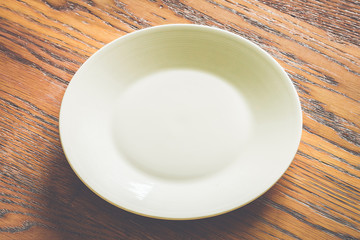 Empty white plate on wood background - vintage filter