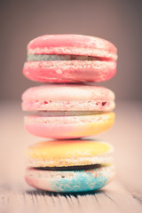 A lot of french colorful macarons on a woody floor in vintage to