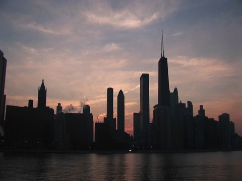 The beautiful Chicago skyline is silhouetted at sunset.