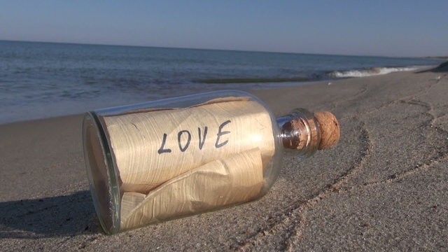 Seascape with transparent bottle with a message love in  sand 