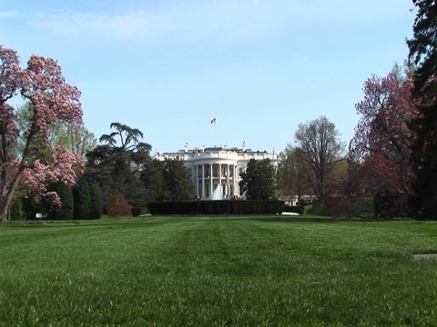 The Camera Zooms-in Across A Lush Green Yard To The Entrance Of The White House.