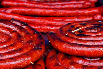 Fry sausages roll in bulk, fixed with wooden rods.