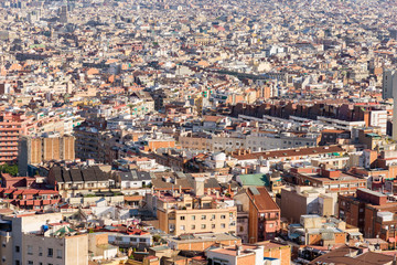 Fototapeta na wymiar Top view from the Park Guinardo, one of the west side hills in Barcelona, to the city Barcelona with a sea of houses and urban canyons. Barcelona is one of the most densely populated cities in Europe 