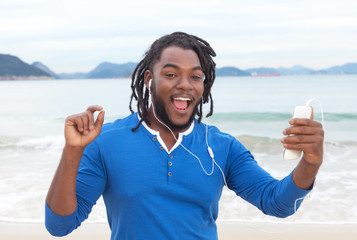Mann mit Rastalocken hört Musik am Strand