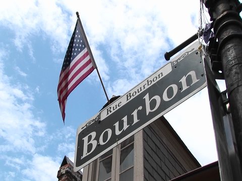 An American flag flies above a street sign identifying New Orleans's famed Bourbon Street.