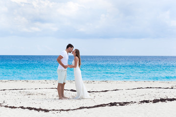 Fototapeta na wymiar Newlyweds kissing on white sandy beach