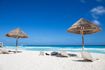 Caribbean sea coastline with grass sun umbrellas and wooden beac