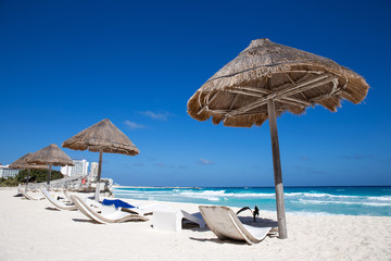 Caribbean sea coastline with grass sun umbrellas and wooden beac