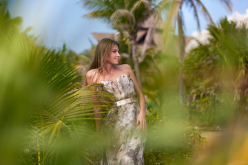 Beautiful woman in dress on a background of palm trees