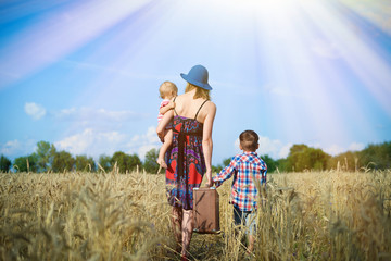 Image of woman wearing hat with baby girl walking away on wheat