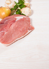 Food background of fresh meat, mushrooms, onion at the wooden board with copy space