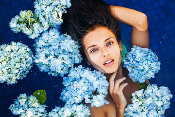dramatic portrait of a woman floating an a swimming pool full of flowers