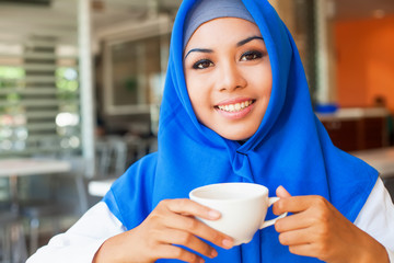 asian muslim woman enjoying a cup of tea