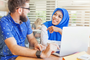 Obraz premium asian muslim woman and caucasian man looking at screen of laptop