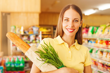 woman buying bread and onion in supermarket, looking at camera