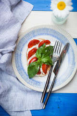 Toast with cherry tomato, mozzarella and basil leaves