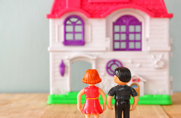 concept image of young couple in front of new house. little plastic toy dolls (male and female) , selective focus.
